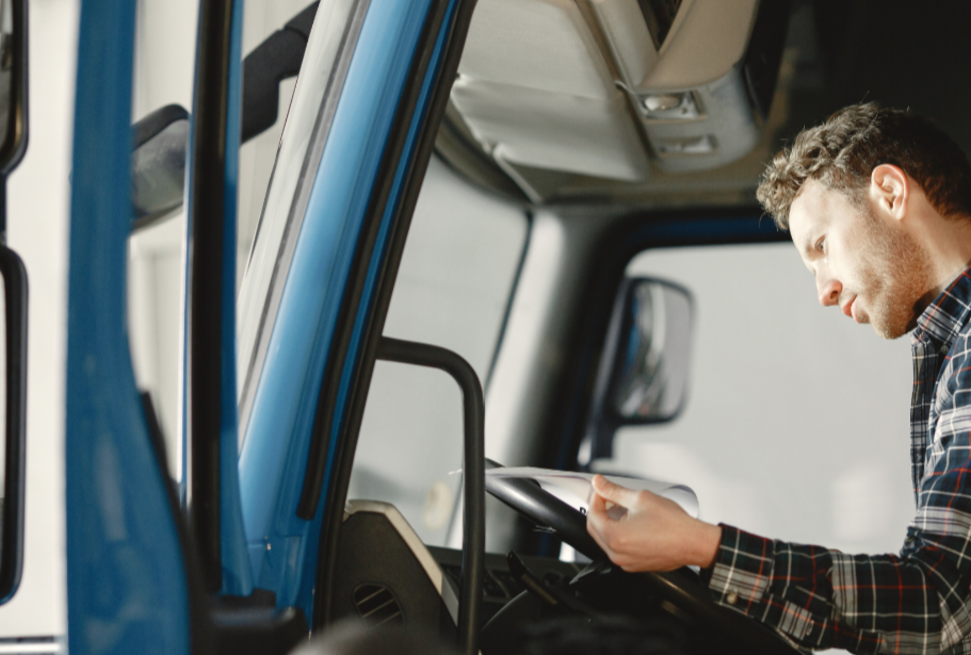 Trucker looking at documents in his cab.